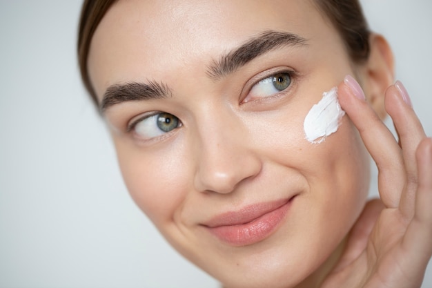 Portrait d'une belle femme à la peau claire à l'aide d'une crème hydratante