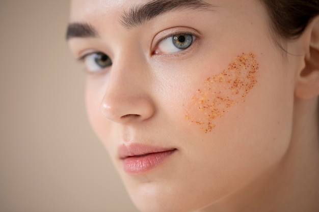 Portrait d'une belle femme à la peau claire à l'aide d'un gommage pour le visage