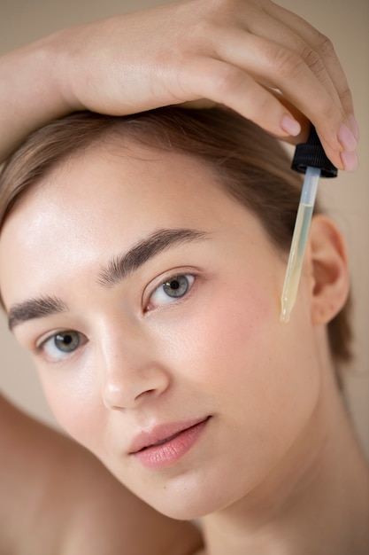 Portrait d'une belle femme à la peau claire à l'aide d'un sérum pour le visage