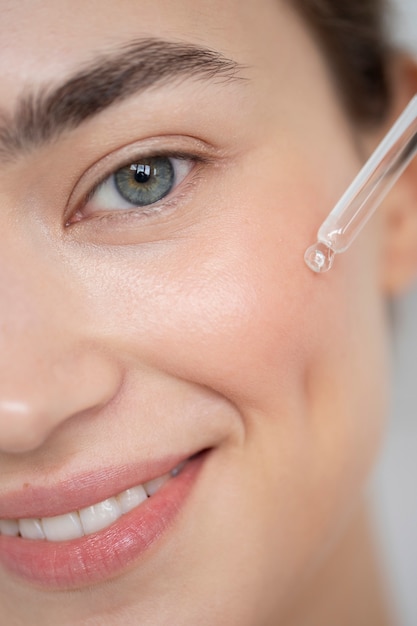 Portrait d'une belle femme à la peau claire à l'aide d'un sérum pour le visage