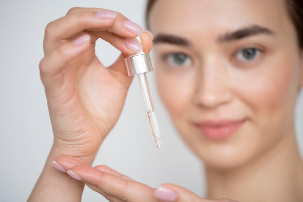 Portrait d'une belle femme à la peau claire à l'aide d'un sérum pour le visage