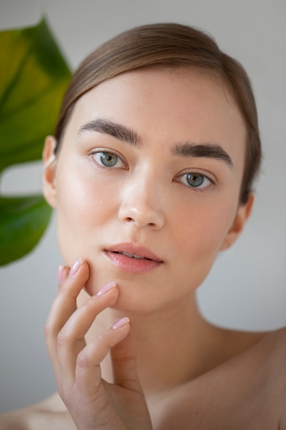 Portrait d'une belle femme à la peau claire posant avec une feuille de plante monstre