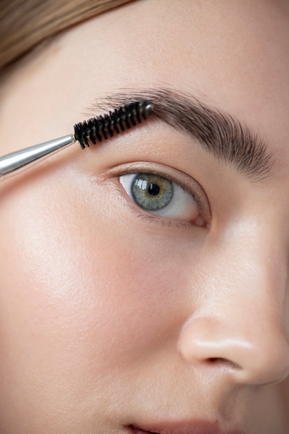 Portrait d'une belle femme à la peau claire se brossant les sourcils