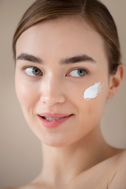 Portrait d'une belle femme à la peau claire utilisant une crème hydratante sur son visage