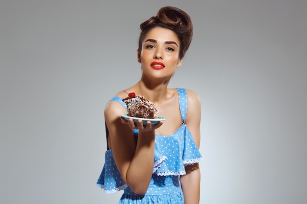 Portrait de la belle femme pin-up tenant le gâteau dans les mains