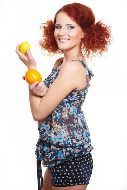 Portrait de la belle femme rousse au gingembre souriant en robe d'été isolé sur blanc avec orange et citron