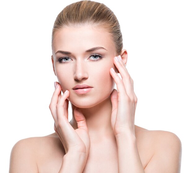 Portrait de la belle femme sensuelle avec une peau saine touchant son visage - isolé sur un mur blanc.