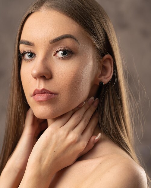 Portrait d'une belle femme avec ses mains sur son cou