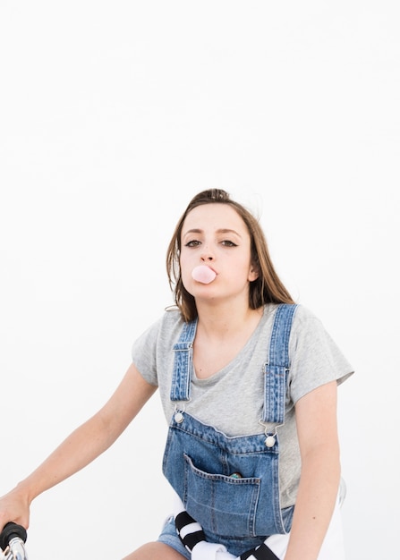Portrait d'une belle femme soufflant du bubble-gum sur fond blanc
