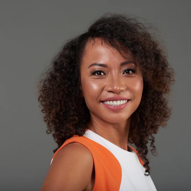 Portrait de la belle femme souriante aux cheveux bouclés, regardant la caméra