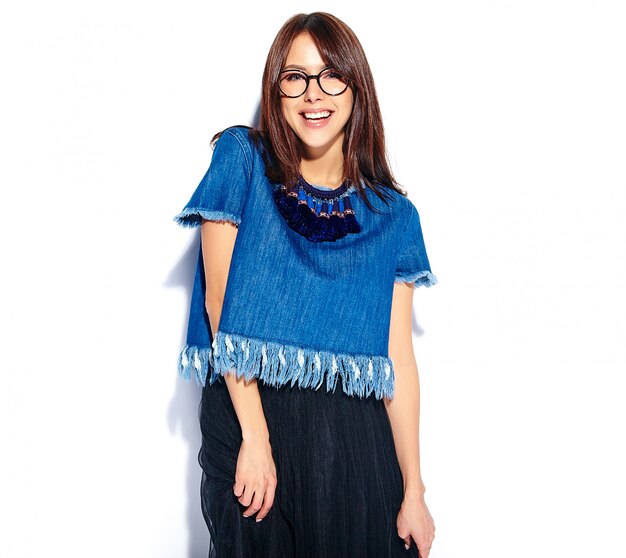 Portrait de la belle femme souriante intelligente hipster brune mannequin dans des vêtements de jeans bleu élégant décontracté et des lunettes isolé sur blanc