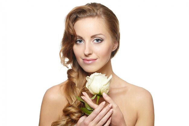 Portrait de belle femme souriante sensuelle avec rose blanche sur fond blanc ong cheveux bouclés, maquillage lumineux