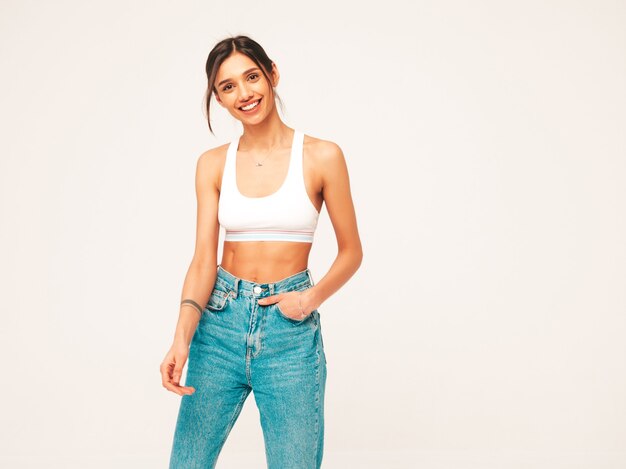 Portrait d'une belle femme souriante vêtue d'une chemise en jersey blanc et d'un jean