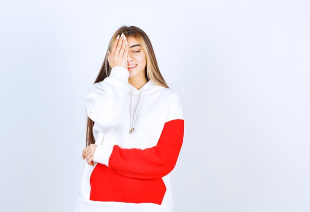 Portrait d'une belle femme en sweat à capuche chaud debout et couvrant un œil avec la main