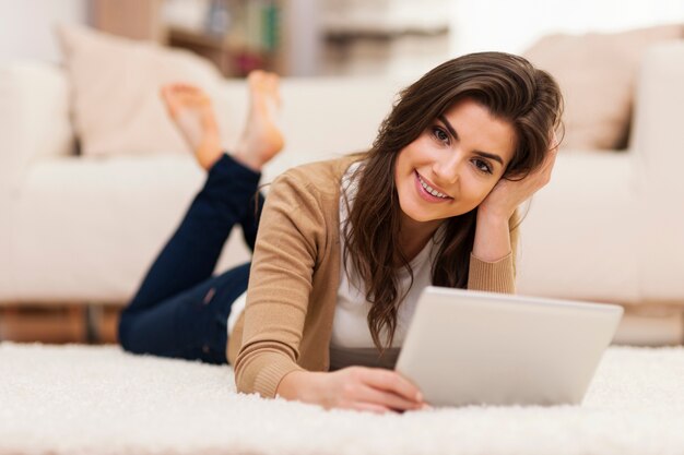 Portrait de la belle femme avec tablette numérique sur tapis