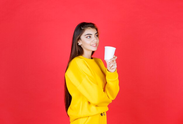 Portrait de belle femme en tenue jaune posant avec une tasse de thé