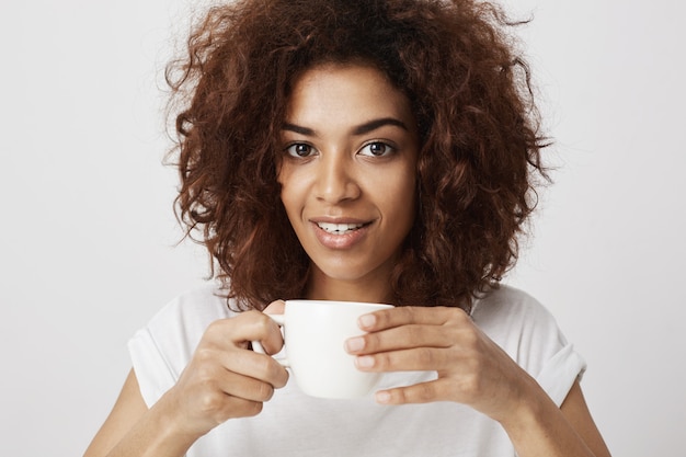 Portrait de la belle fille africaine souriante tenant la tasse de café.