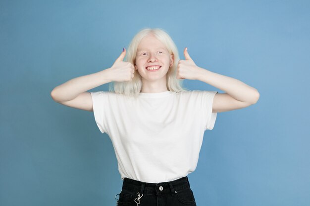 Portrait de belle fille albinos caucasienne isolée sur mur bleu