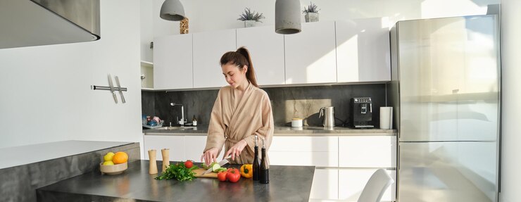 Photo gratuit portrait d'une belle fille brune coupant des légumes pour préparer des repas et de la salade dans la cuisine en train de manger