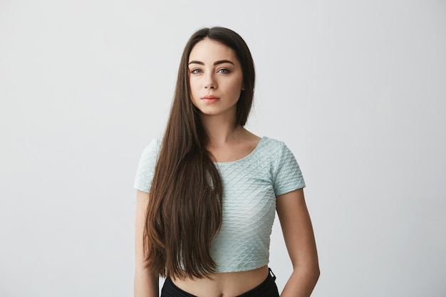 Portrait D'une Belle Fille Brune Avec Un Maquillage Naturel Regardant à L'avant Sur Un Mur Blanc