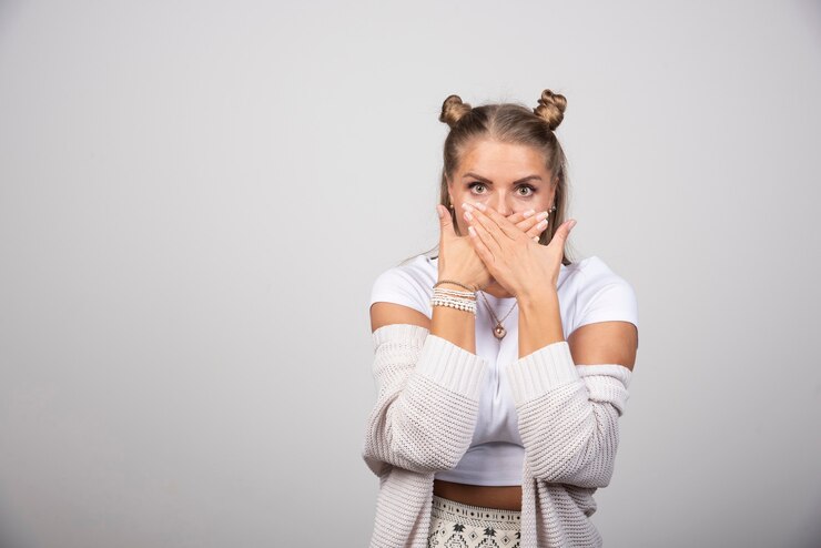 Photo gratuit portrait de belle fille couvrant sa bouche sur fond gris.