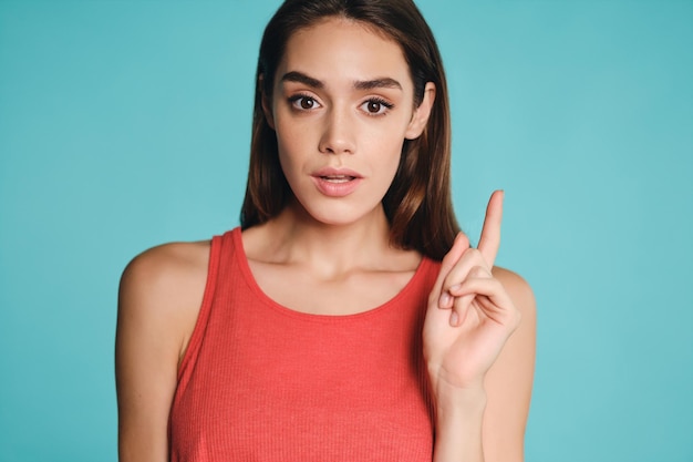 Portrait d'une belle fille décontractée ayant une idée pensivement regardant à huis clos sur fond coloré isolé