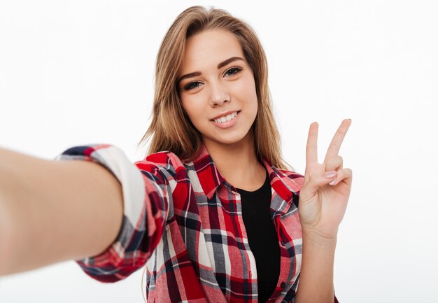 Portrait d'une belle fille heureuse en chemise à carreaux prenant un selfie