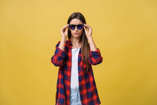 Portrait d'une belle fille à lunettes rondes sur fond jaune en studio