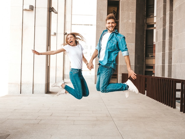 Portrait de belle fille souriante et son beau petit ami dans des vêtements d'été décontractés. Bonne famille joyeuse sautant et s'amusant sur le fond de la rue. Devenir fou