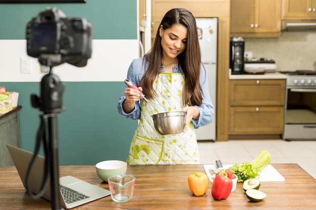 Photo gratuite portrait d'une belle jeune blogueuse culinaire préparant de la nourriture et enregistrant une vidéo à la maison