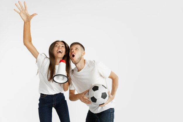 Portrait de la belle jeune couple de fans de football ou de football sur le mur de studio blanc