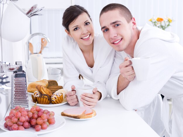 Portrait de la belle jeune couple souriant prenant son petit déjeuner dans le kithen
