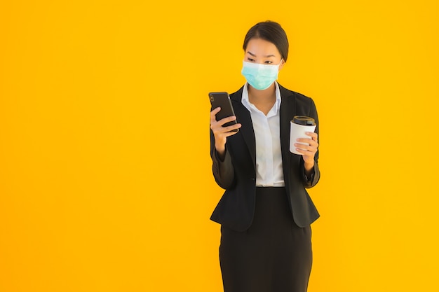 Portrait belle jeune entreprise asiatique femme porter un masque utiliser un téléphone mobile avec du café
