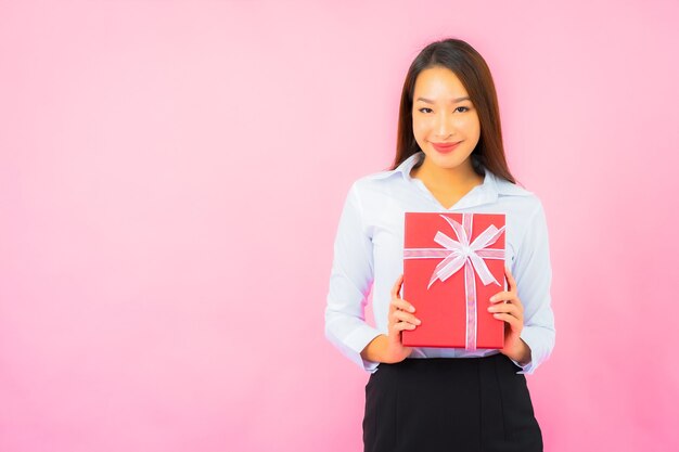 Portrait belle jeune femme d'affaires asiatique avec boîte-cadeau rouge sur mur de couleur rose