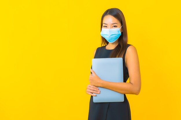 Portrait belle jeune femme d'affaires asiatique porter un masque pour protéger covid19 avec ordinateur portable