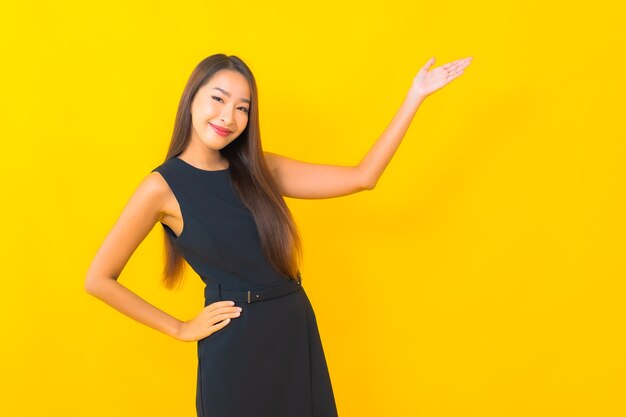 Portrait belle jeune femme d'affaires asiatique sourire avec action sur fond de couleur jaune