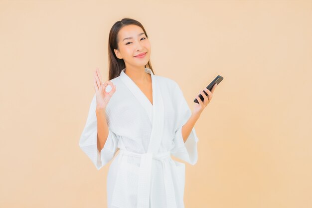 Portrait belle jeune femme asiatique à l'aide de téléphone mobile intelligent sur beige