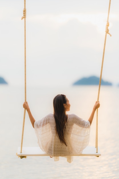 Photo gratuite portrait belle jeune femme asiatique assise sur la balançoire autour de la mer, mer, océan pour se détendre