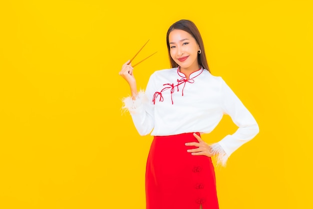 Portrait belle jeune femme asiatique avec des baguettes prêtes à manger sur jaune