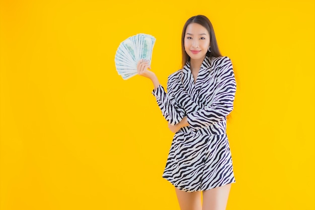 Portrait belle jeune femme asiatique avec beaucoup d'argent et d'argent sur jaune