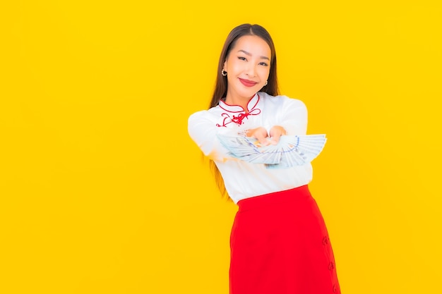 Portrait belle jeune femme asiatique avec beaucoup d'argent et d'argent sur jaune