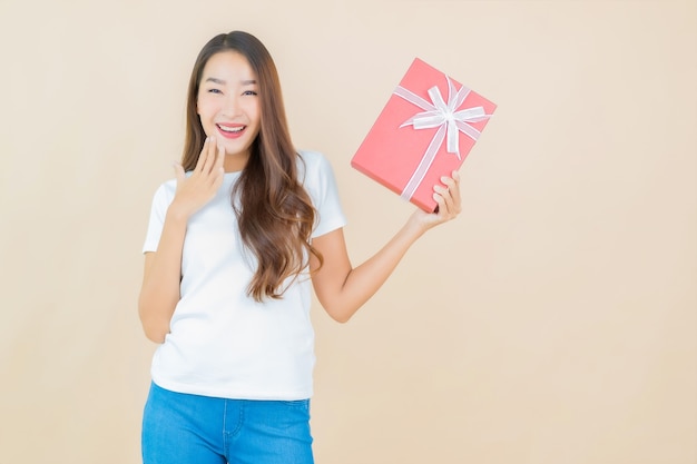 Portrait belle jeune femme asiatique avec boîte-cadeau rouge sur beige