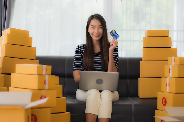 Portrait de la belle jeune femme asiatique avec des boîtes de colis en carton et carte de crédit