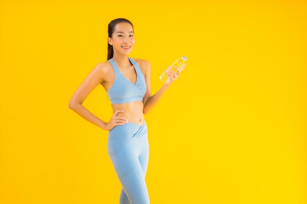Portrait belle jeune femme asiatique avec une bouteille d'eau sur jaune