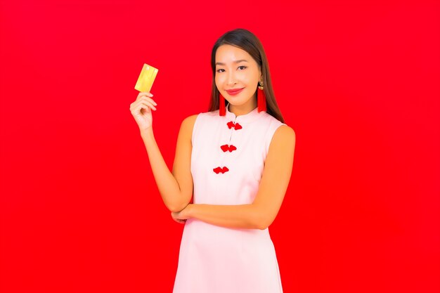 Portrait belle jeune femme asiatique avec carte de crédit sur mur isolé rouge