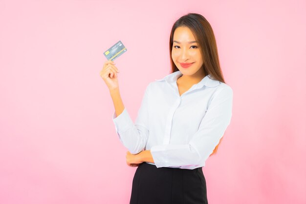 Portrait belle jeune femme asiatique avec carte de crédit sur mur rose