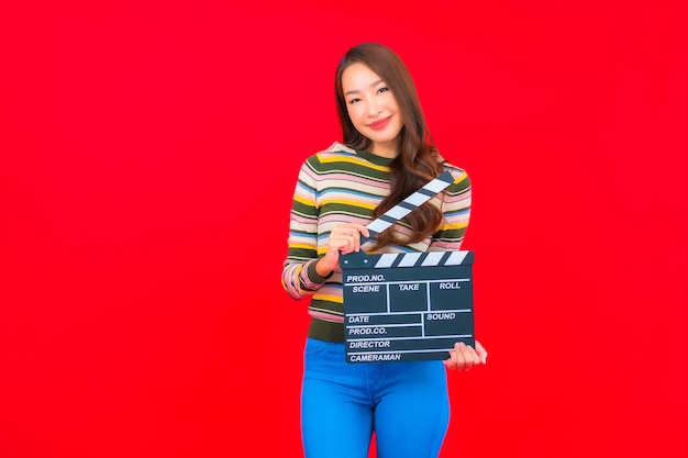 Portrait belle jeune femme asiatique avec coupe ardoise de film sur mur isolé rouge