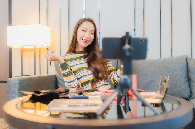 Portrait de la belle jeune femme asiatique critiques et utilise des cosmétiques sur le canapé