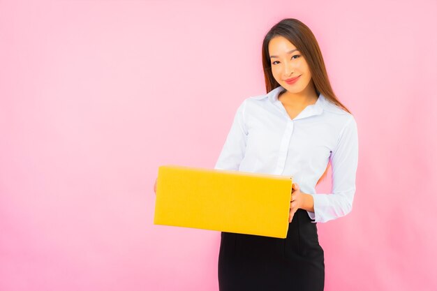 Portrait belle jeune femme asiatique avec emballage de boîte prêt à être expédié sur un mur de couleur rose