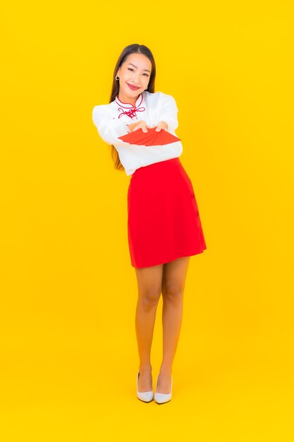Portrait belle jeune femme asiatique avec des enveloppes rouges lettre au nouvel an chinois sur jaune